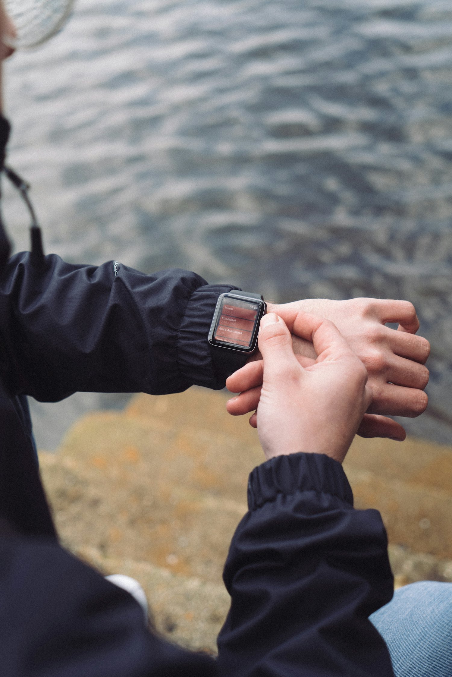 Checking an Apple Watch outdoors by the water.